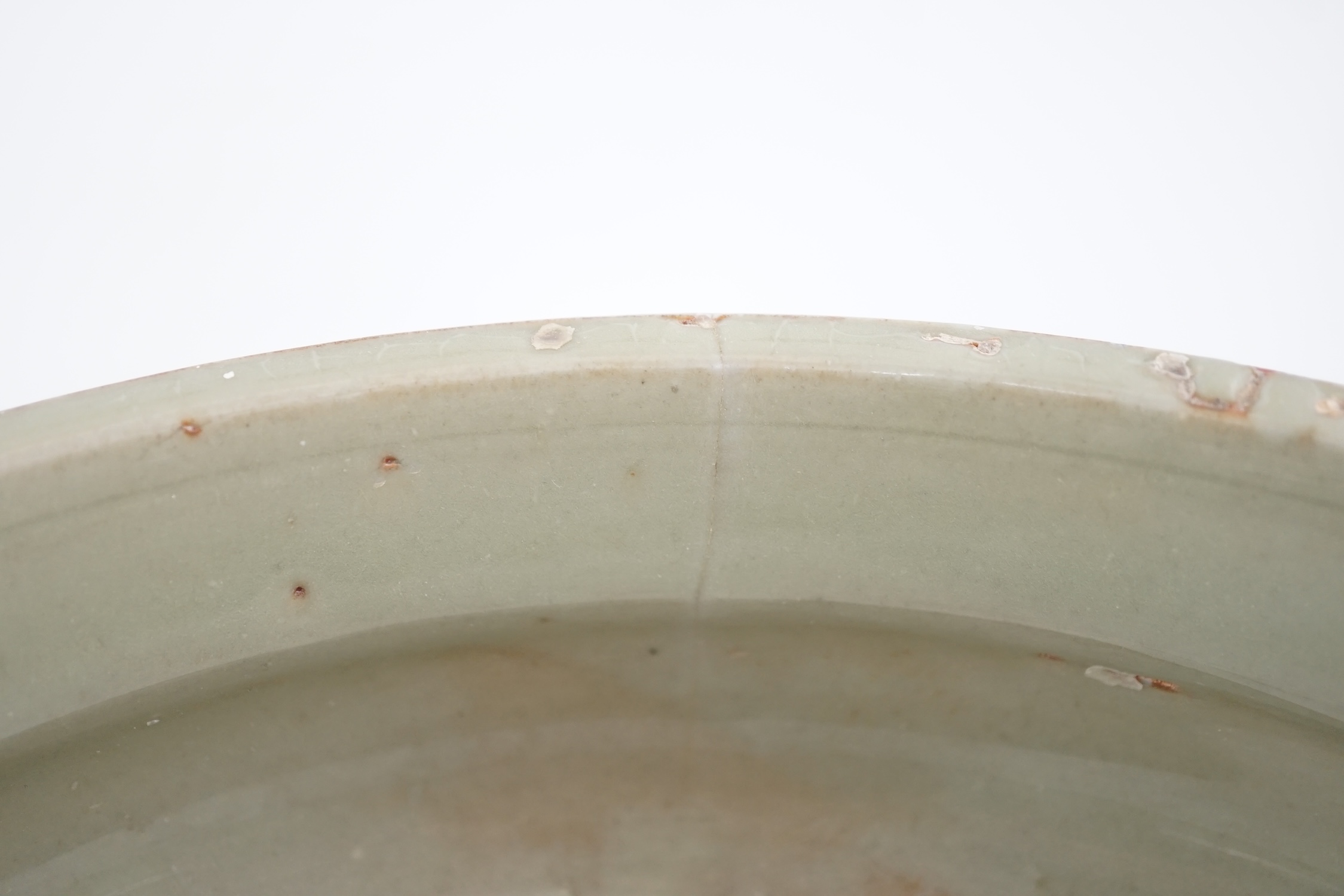 A Chinese Ming Longquan celadon tripod censer, 14th/15th century, the exterior incised with scrolling foliage, on three animal mask feet, burnt orange ring to base, 26.7cm diameter, original receipt for Wing Kei curios,